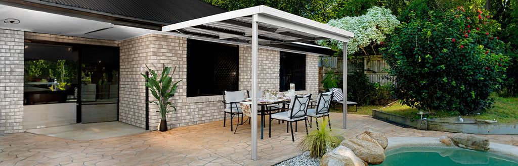 A steel patio cover attached to a house, over a small dining table.