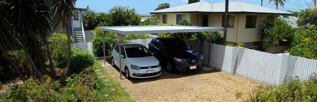 A large skillion carport protecting two cars in a driveway.